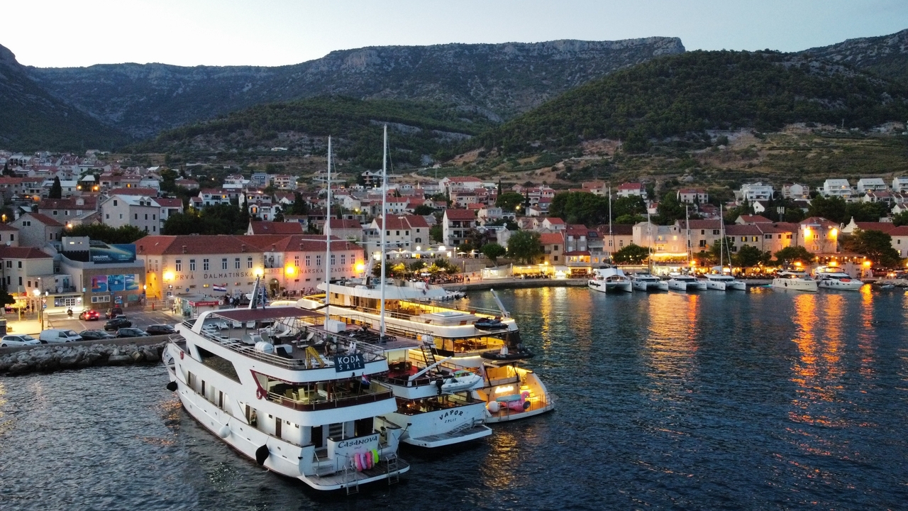 Port au crépuscule avec des yachts et des bâtiments illuminés.