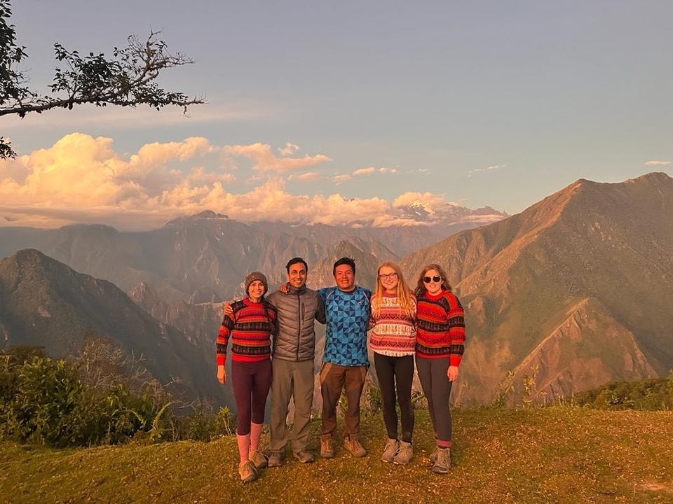 Group of friends in matching sweaters with mountain backdrop.