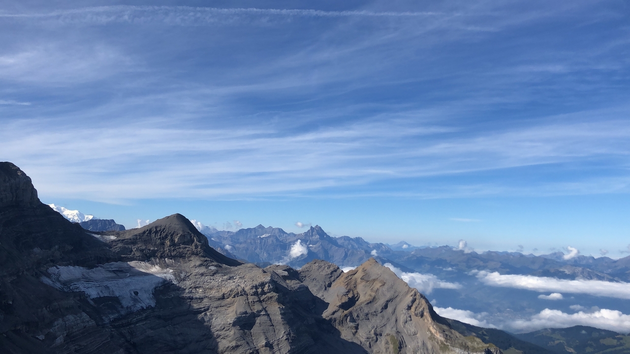 Majestic mountain peaks above clouds with clear sky.