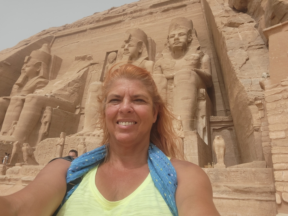 A woman posing with ancient Egyptian statues in the background.