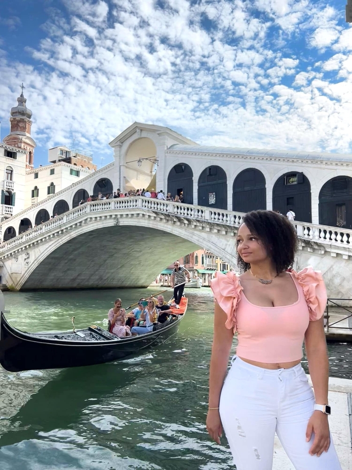 Woman in front of the Rialto Bridge over a canal in Venice.