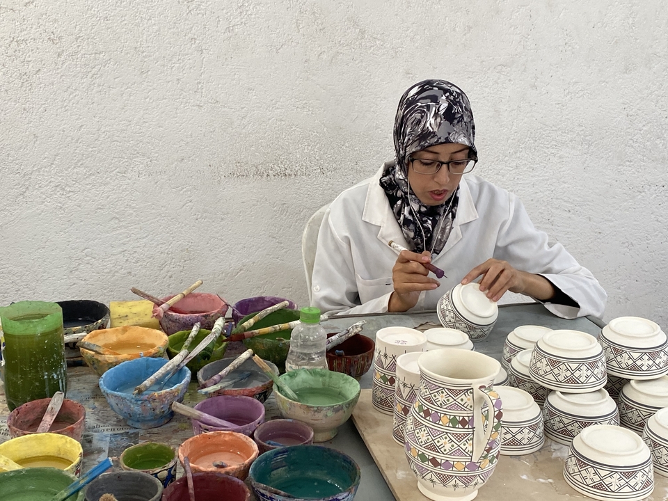 Woman painting pottery with various colored paints.