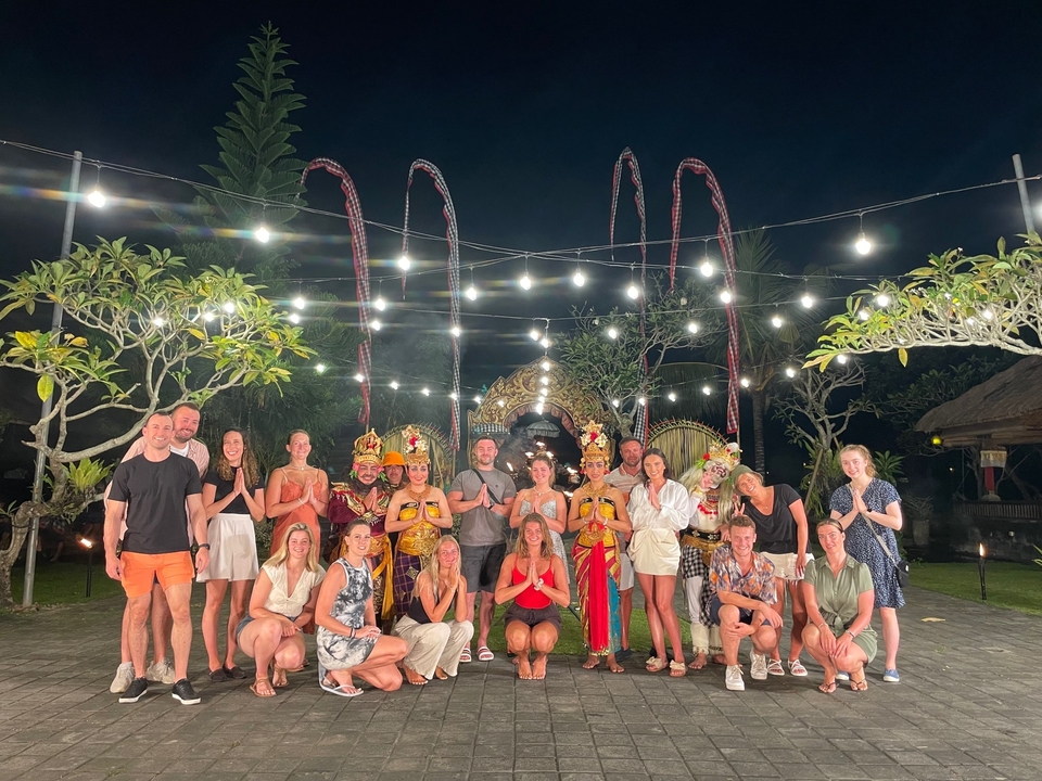 A group of people in traditional costumes under decorative lights at night.