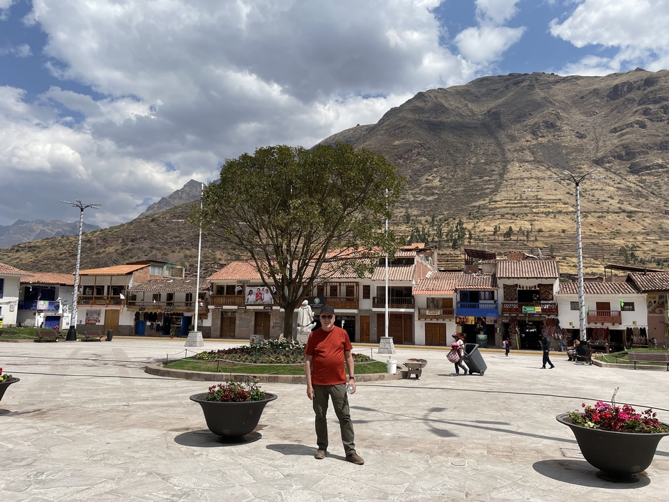 Homme sur une place de ville avec un arrière-plan de montagnes.