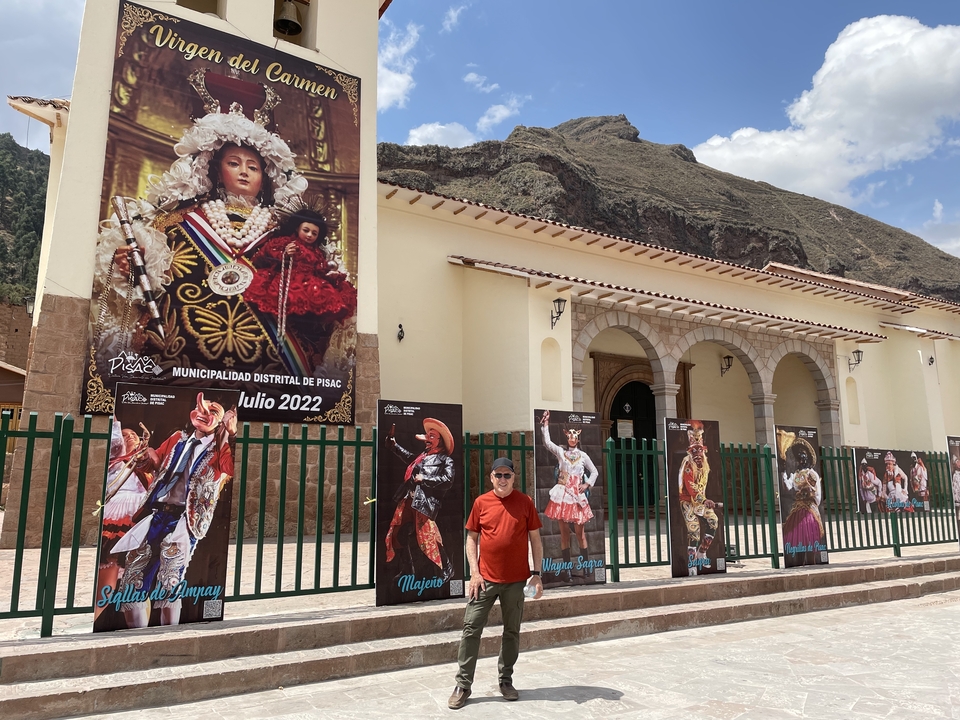 Homme debout devant des affiches de festival colorées à l'extérieur d'un bâtiment.