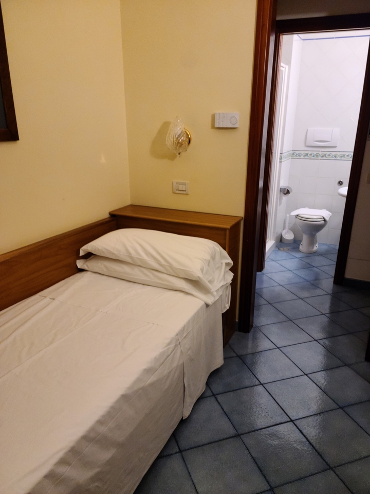Simple hotel room with a bed and adjacent bathroom.