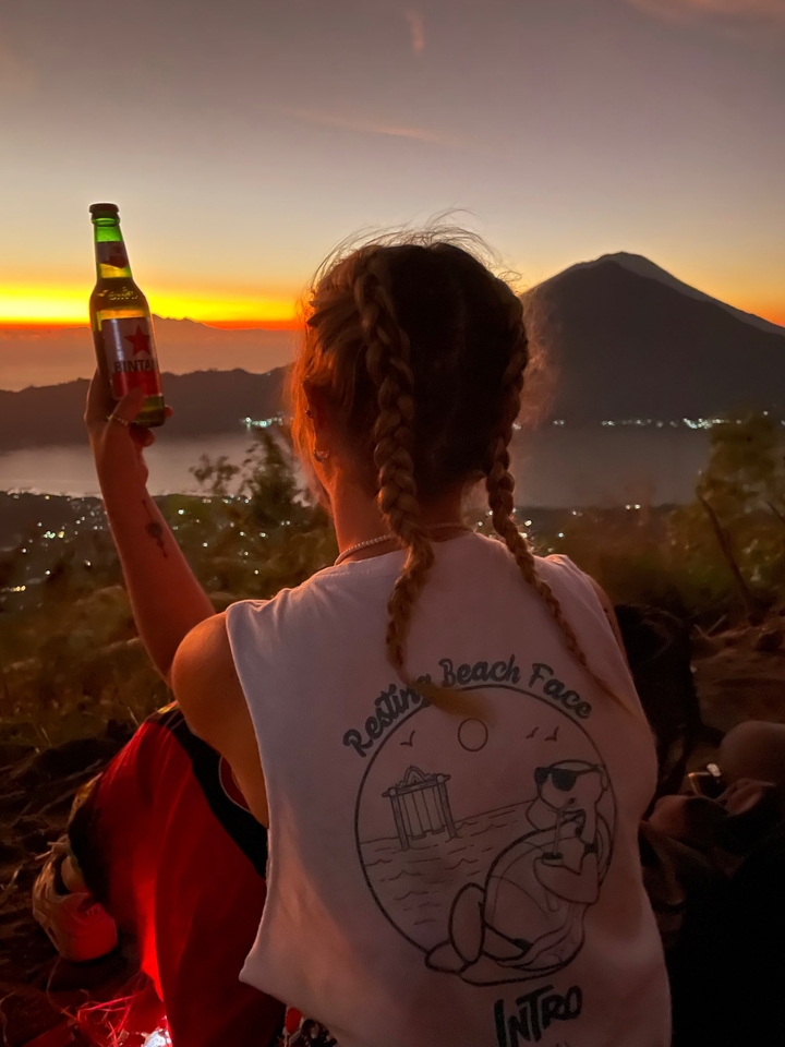 Person in front of a sunset with mountains in the background.