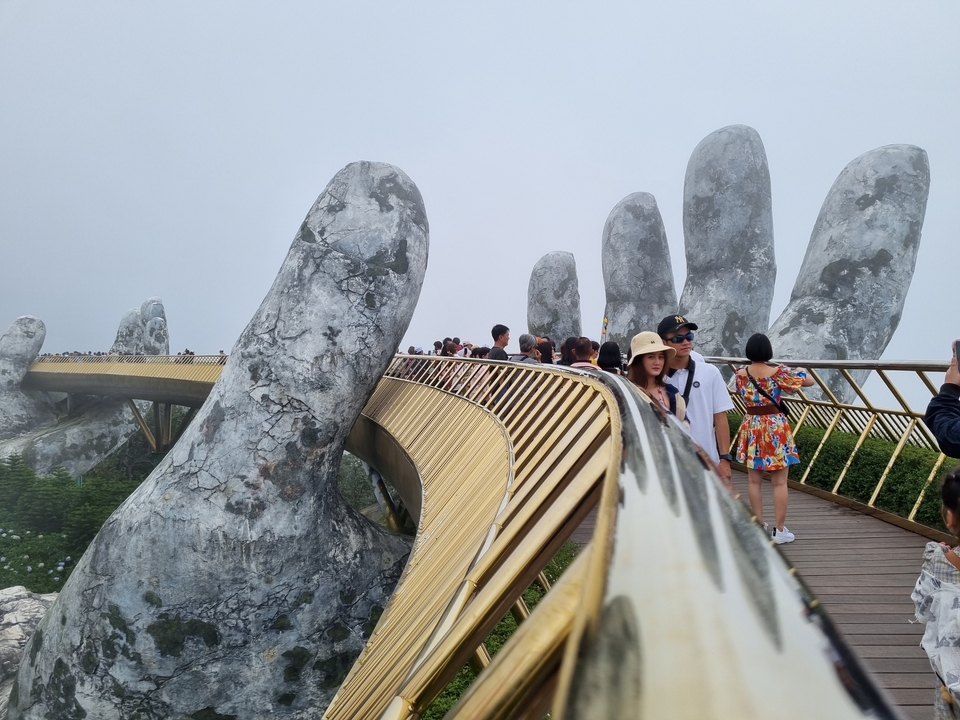 Tourists on the Golden Bridge with giant hands.