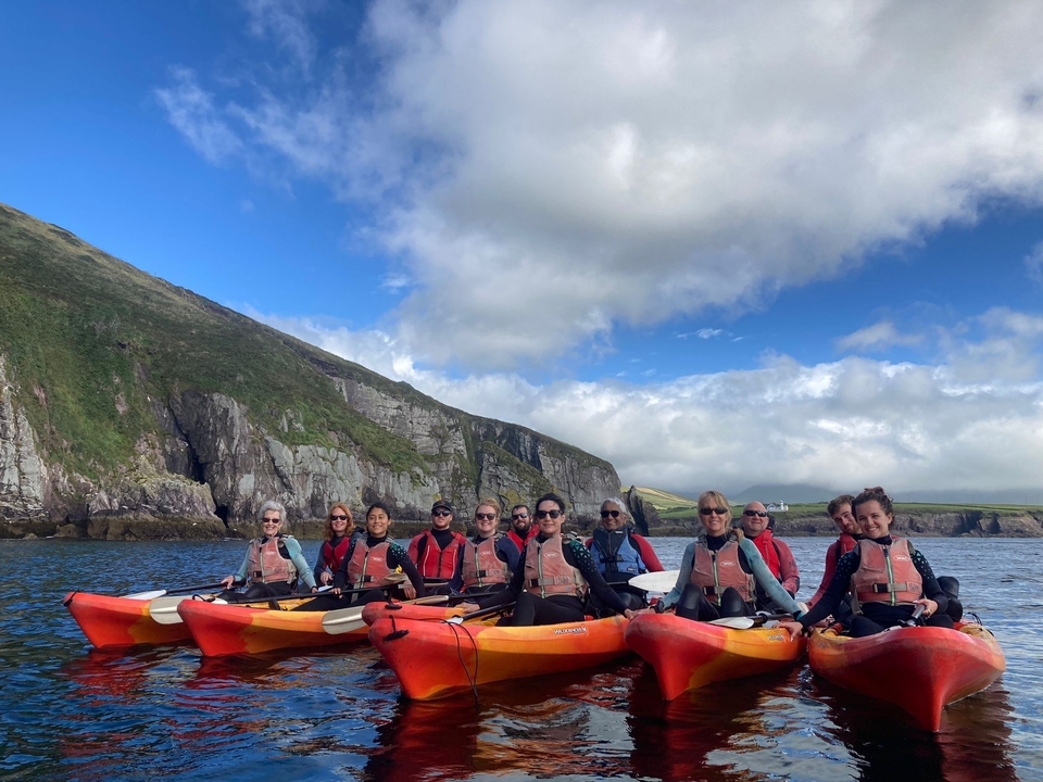 Kayakers posed on the water with cliffs in the background.