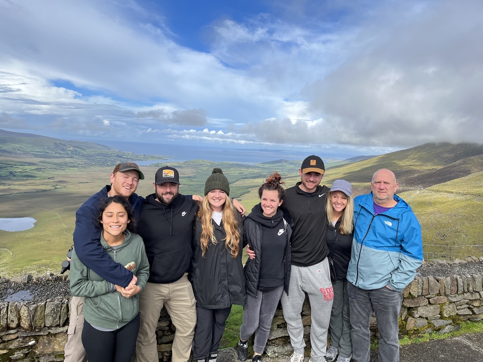 Group of people posing with a scenic mountainous backdrop.