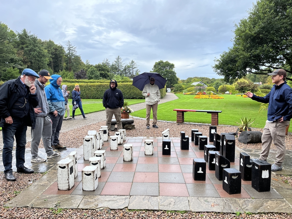 People observing a large outdoor chess game.