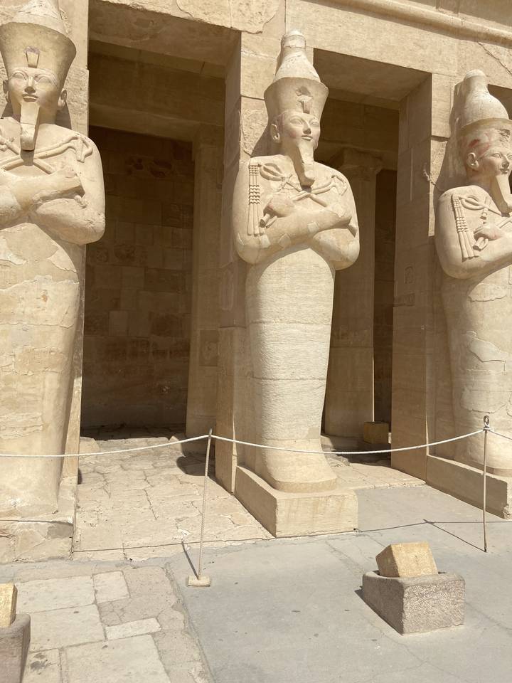 Egyptian statue with crossed arms at a historical site.