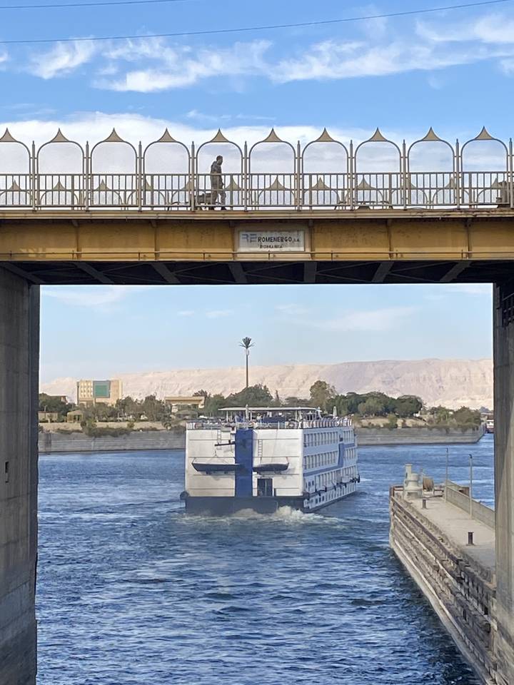 Boat passing under a bridge on a river.