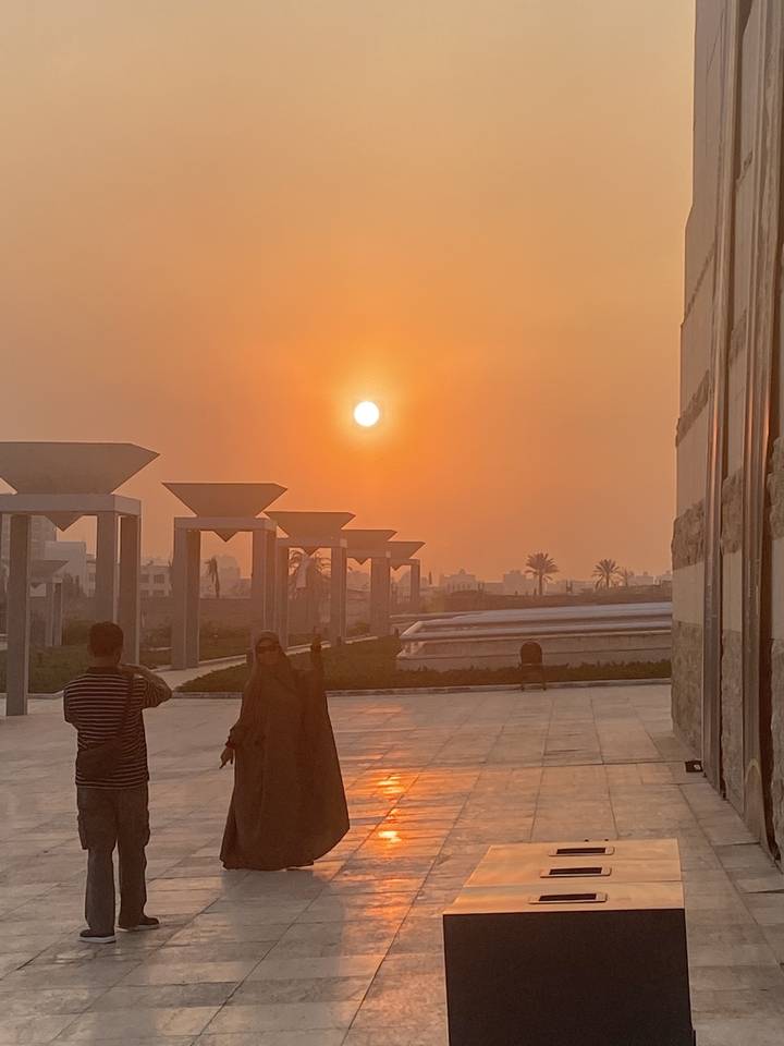 Silhouetted sunset view over a modern architectural setting.