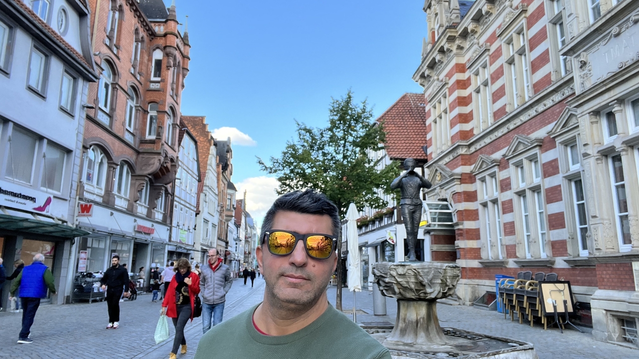 Homme posant dans une rue avec des bâtiments historiques.