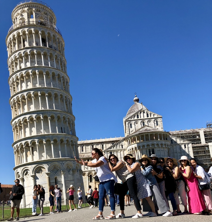 People posing in front of the Leaning Tower of Pisa.