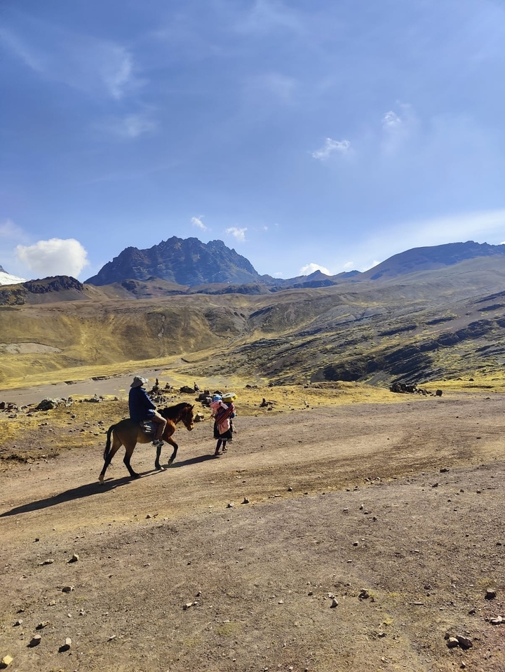 Des gens à cheval et à pied dans une région montagneuse.