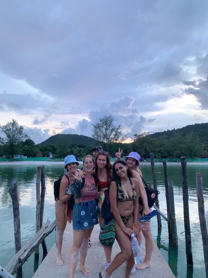 Group of friends posing by the water in a scenic location.