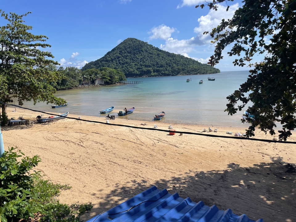 A beach with boats and a hill in the background.