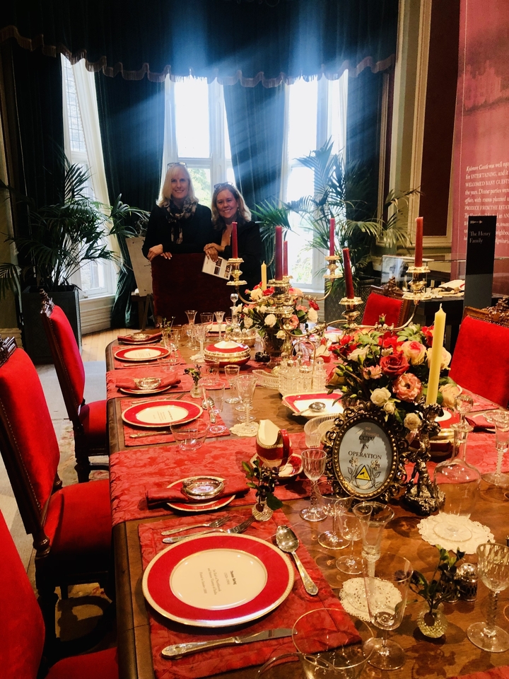 Opulently set dining table with two women standing behind.