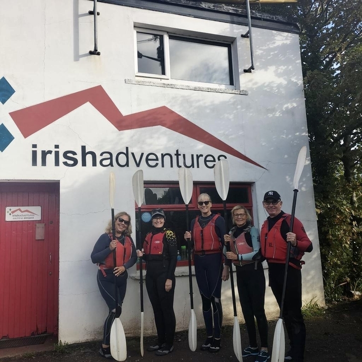 Groupe de personnes tenant des pagaies devant 'Irish Adventures'.