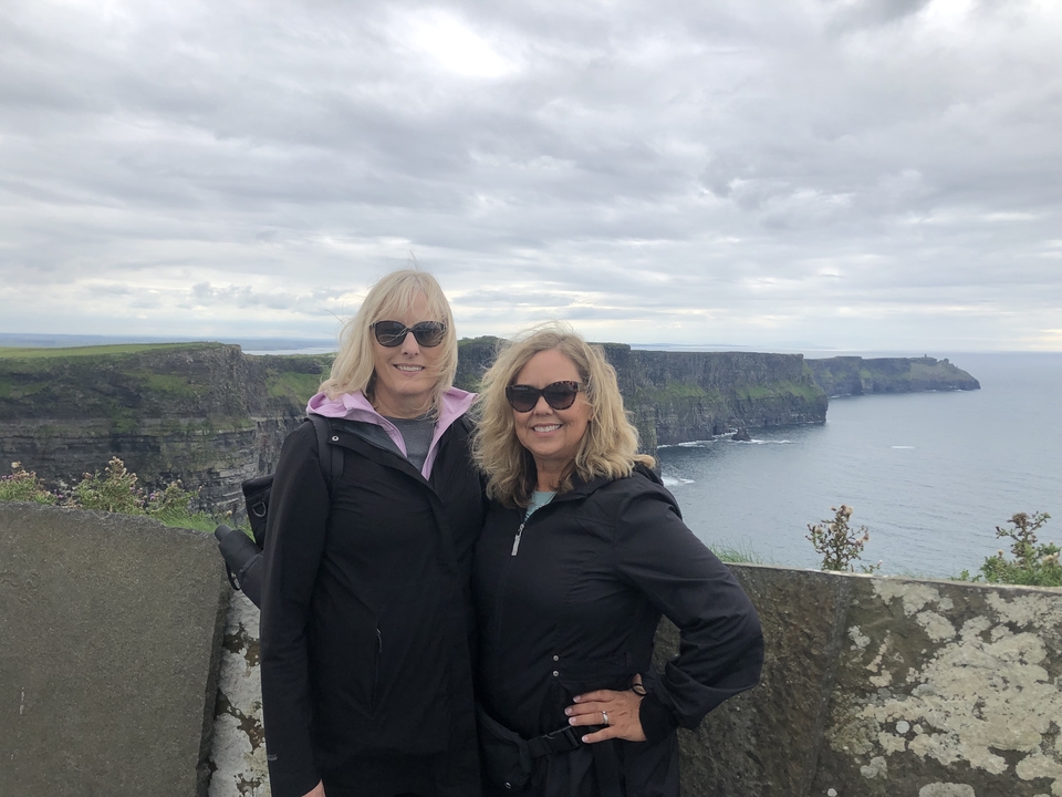 Two women standing in front of the Cliffs of Moher.