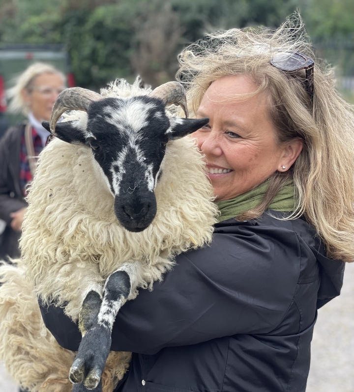 Femme tenant un mouton avec un sourire.