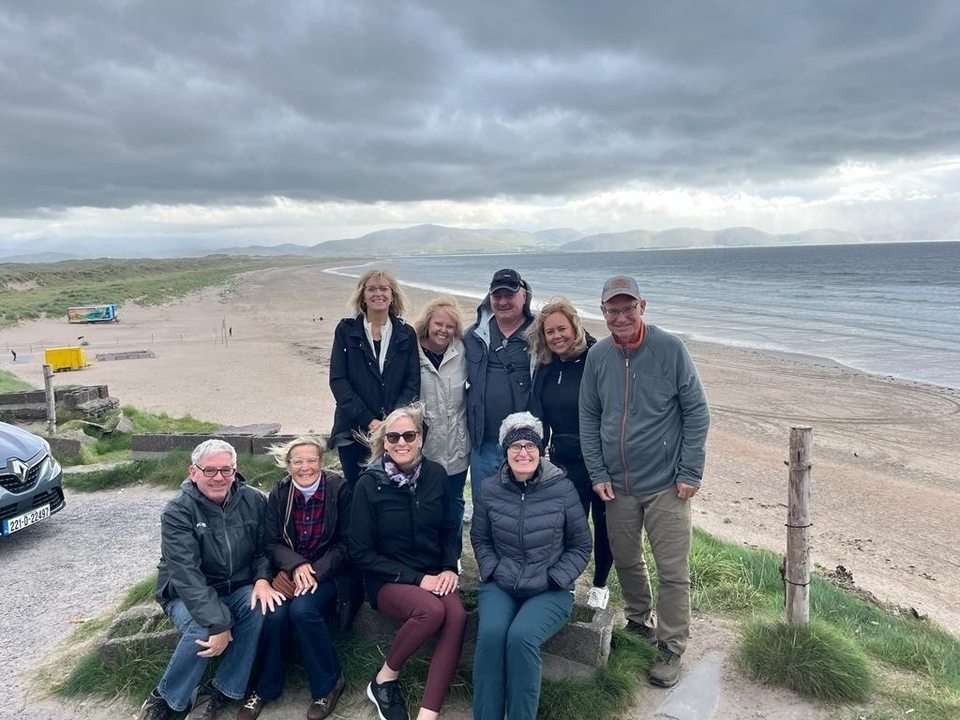 Photo de groupe sur une plage avec des montagnes en arrière-plan.