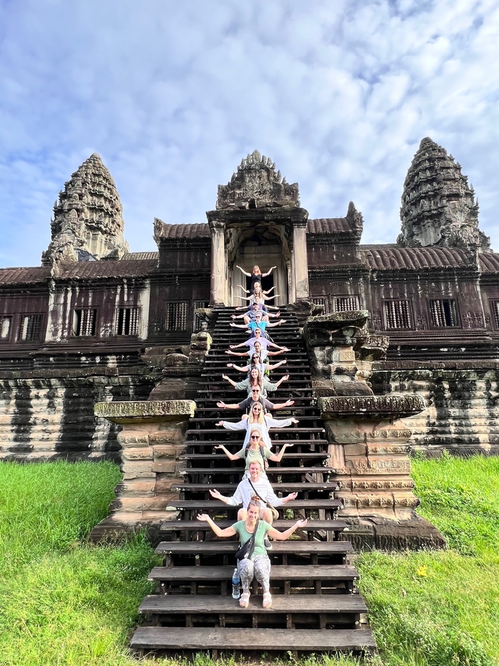 Group of people standing on ancient temple steps in a formation.