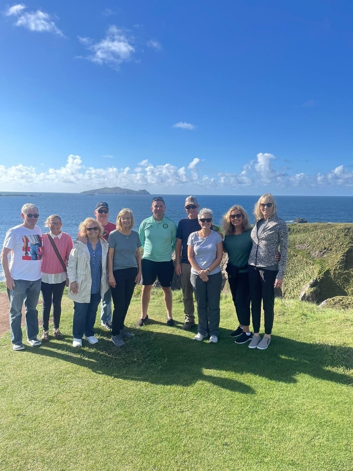 Un groupe de personnes posant ensemble avec une falaise côtière pittoresque en arrière-plan.