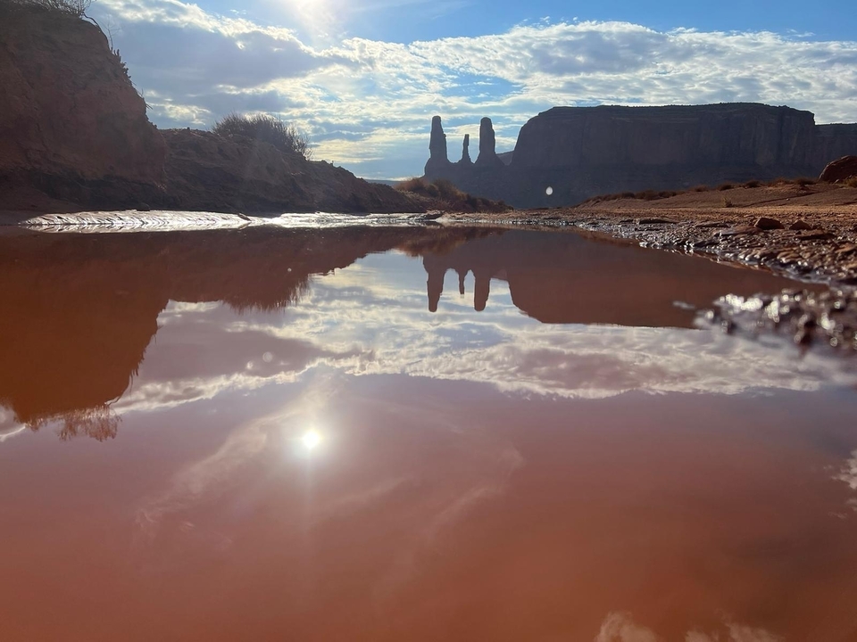 Rock formations reflected in a small body of water at sunset.