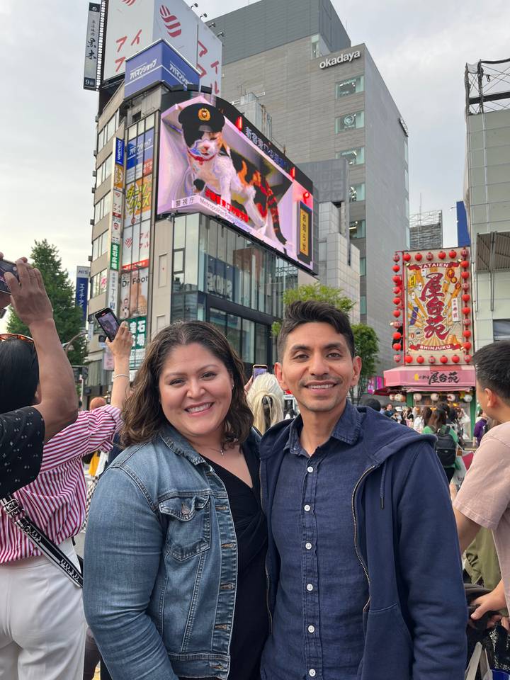 Two people smiling with cityscape in the background.
