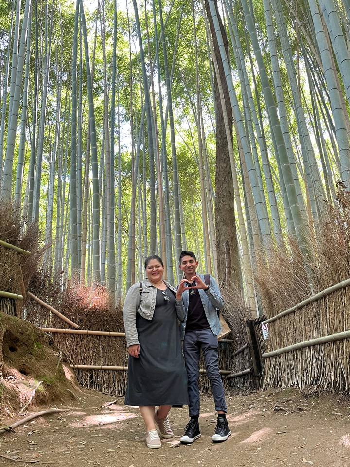 Two people standing among tall bamboo trees.