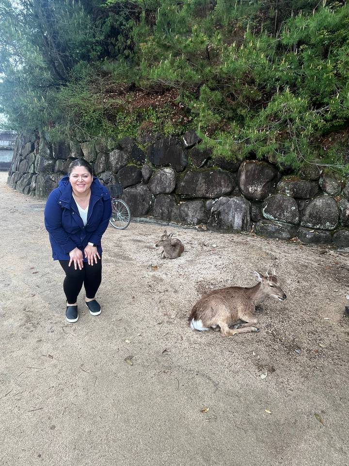 Person smiling next to a resting deer.