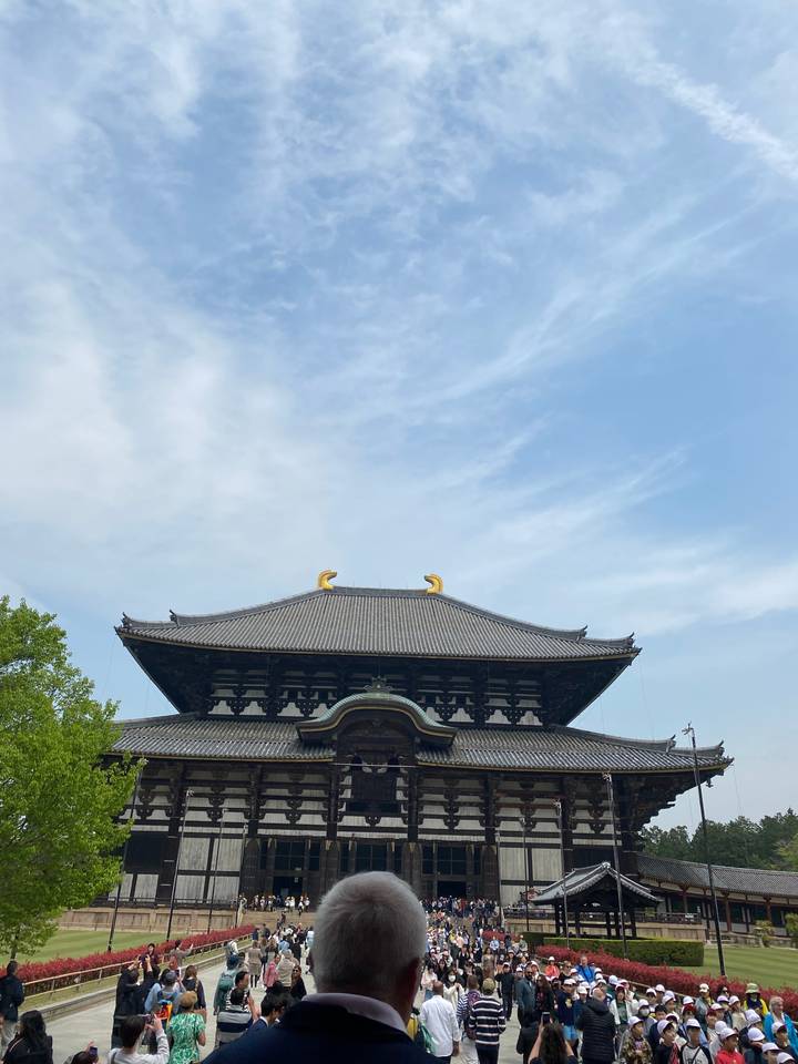 Large historic temple with intricate roof design, crowded with tourists.