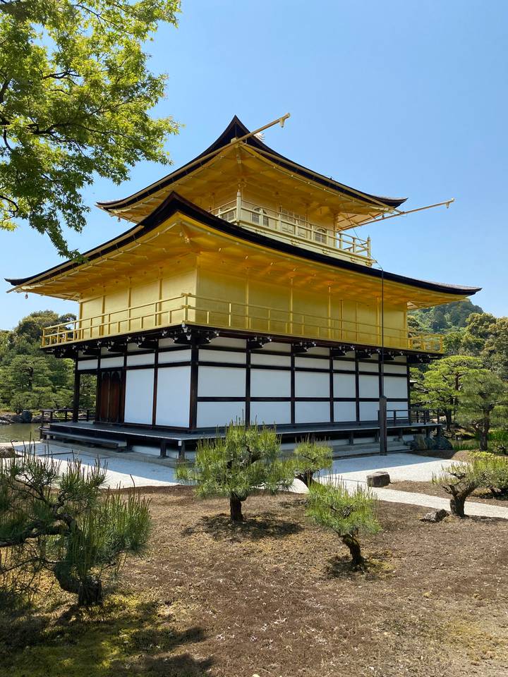 Golden pavilion with trees and serene surroundings.