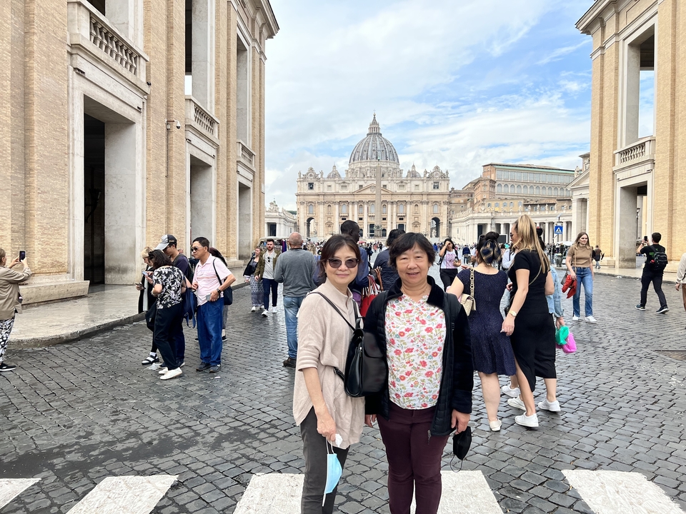 Tourists posing with St. Peter's Basilica in the background.