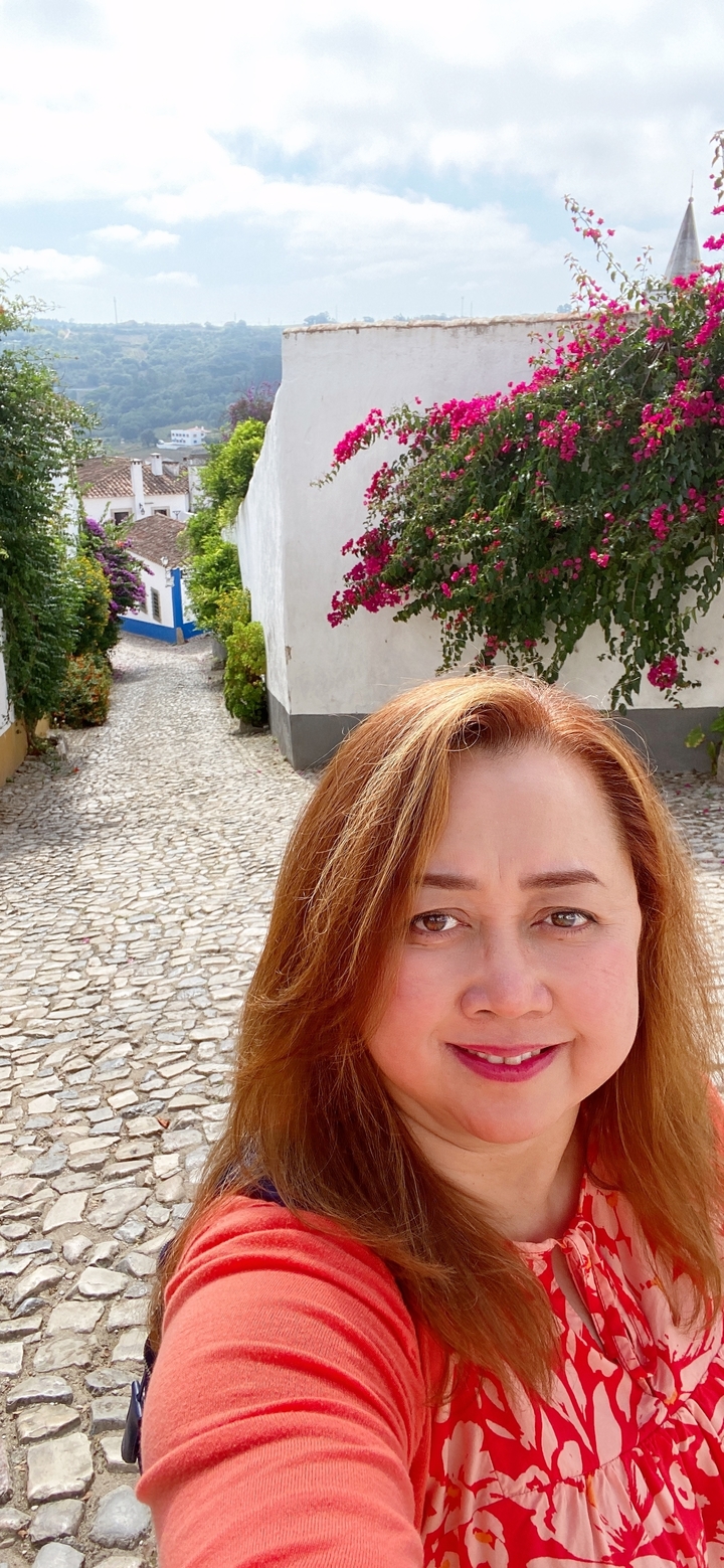 Femme prenant un selfie dans une rue pavée.