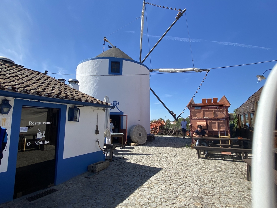 Moulin à vent traditionnel aux murs blancs avec une enseigne de restaurant.