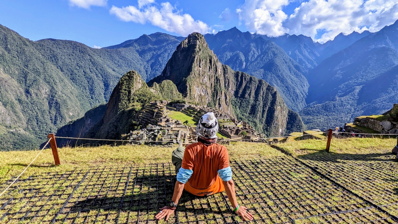 Vue panoramique du Machu Picchu avec une personne admirant le paysage.