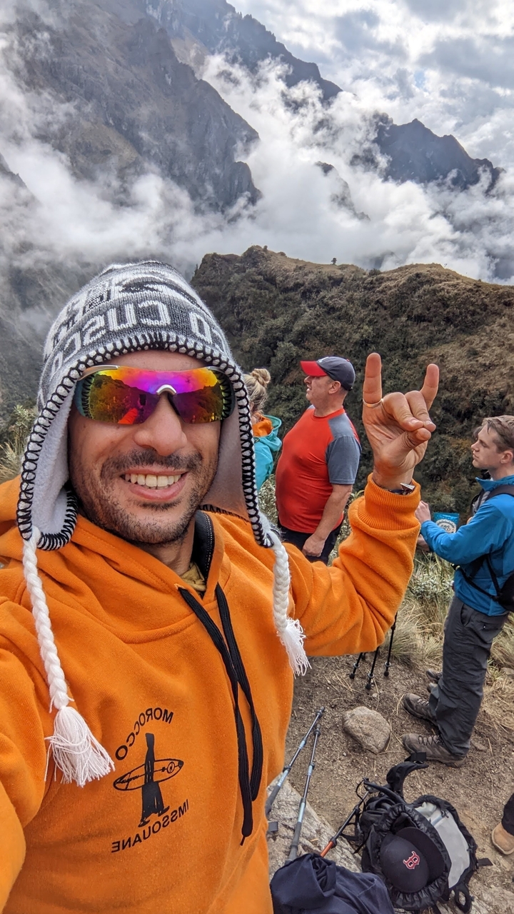 Selfie en gros plan d'une personne avec d'autres randonneurs en arrière-plan.