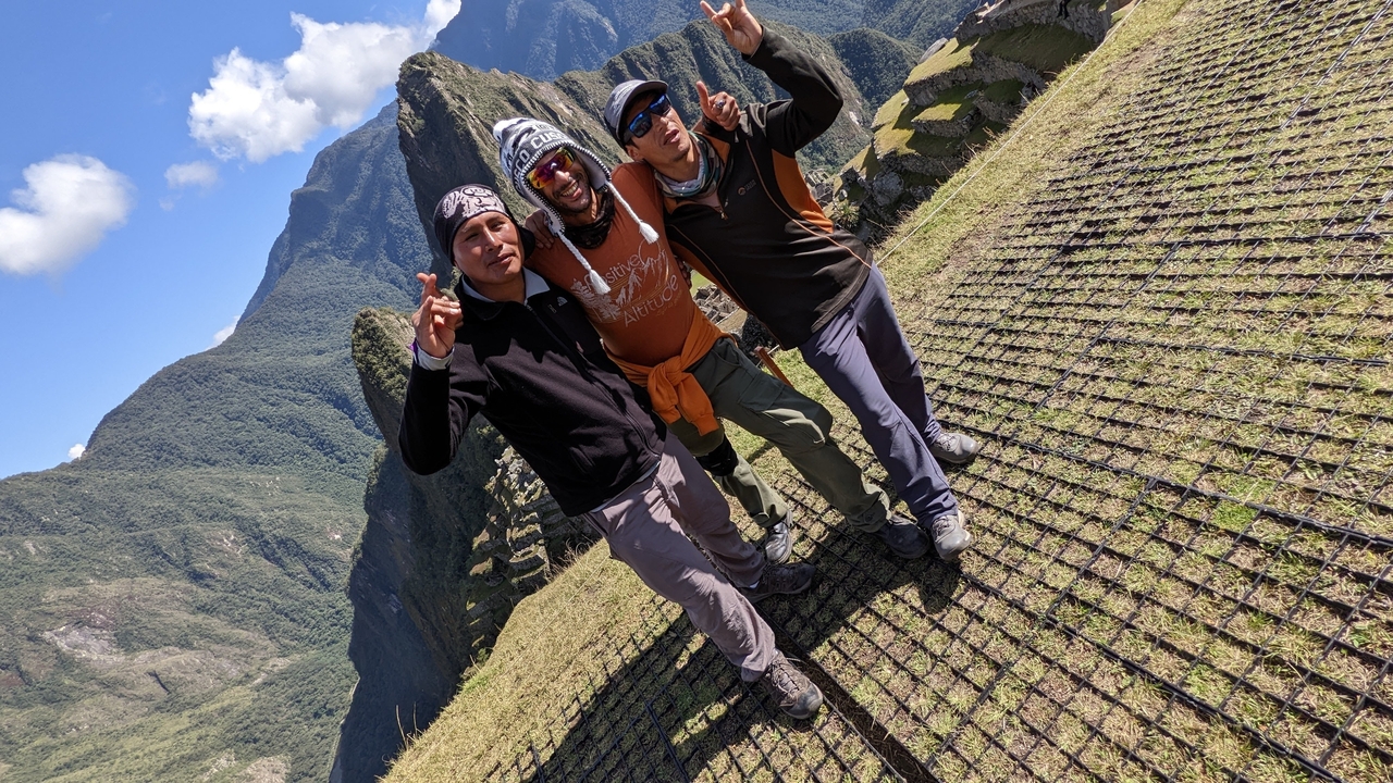 Trois personnes debout ensemble sur un point de vue panoramique au Machu Picchu.