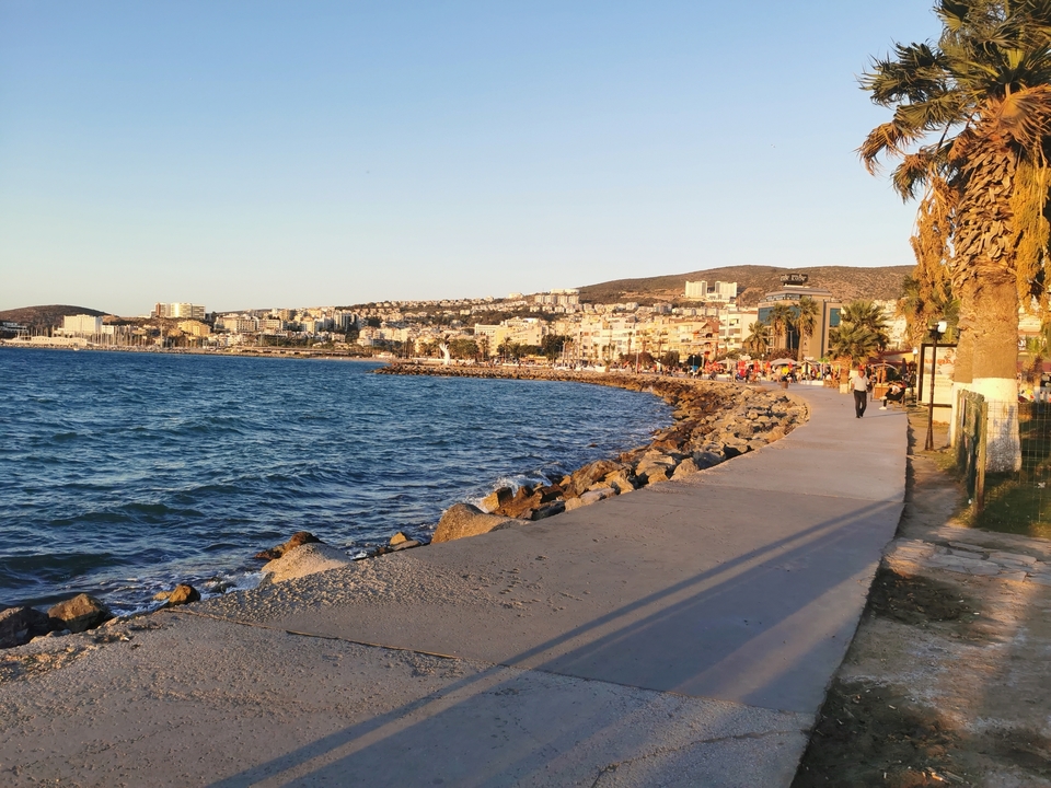 Coastal walkway with a view of the ocean and city.