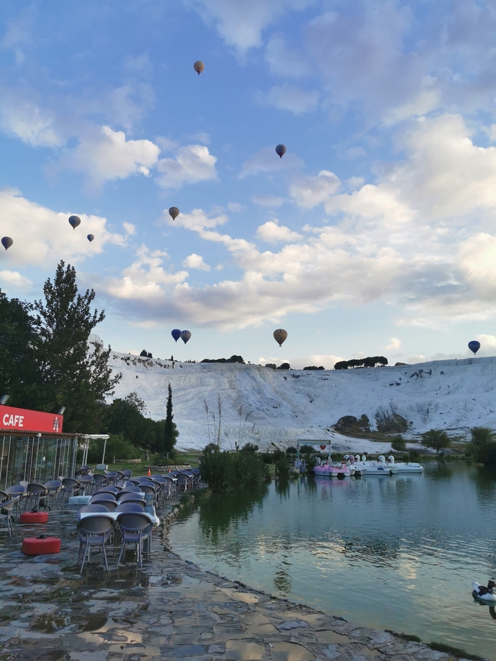 Hot air balloons floating over white cliffs at sunrise.