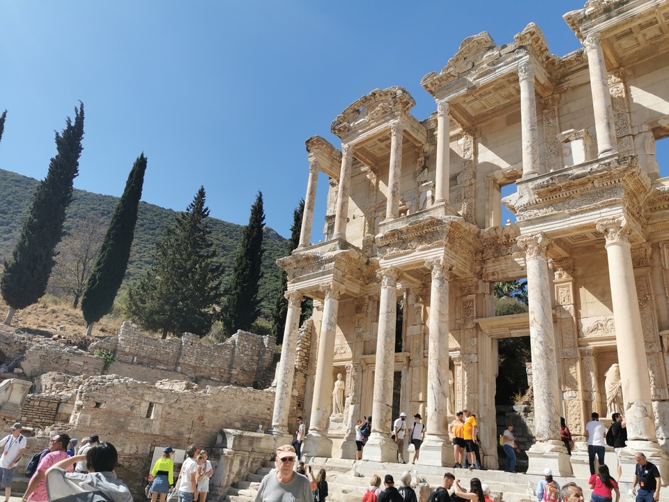 Historical library ruins with people wandering around.