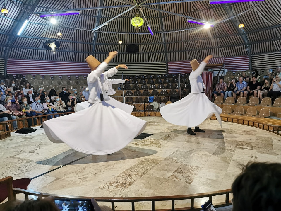 Dancers performing a traditional whirling dance inside a venue.