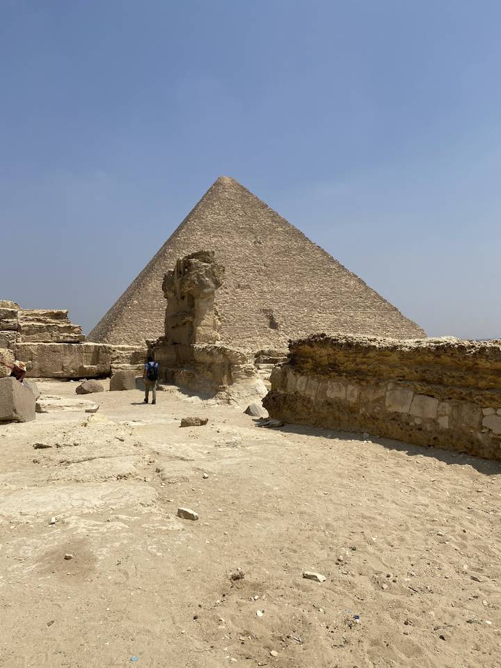 Een persoon die staat in de buurt van een piramide in een woestijnomgeving.