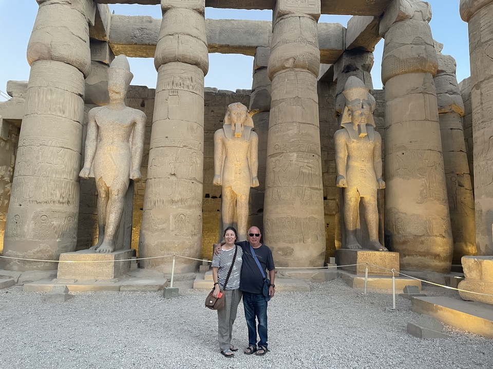 Tourists posing in front of large ancient statues.