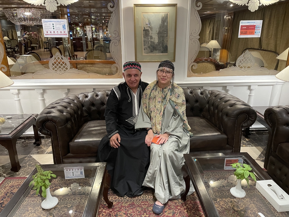 Couple wearing traditional attire sitting on a couch.