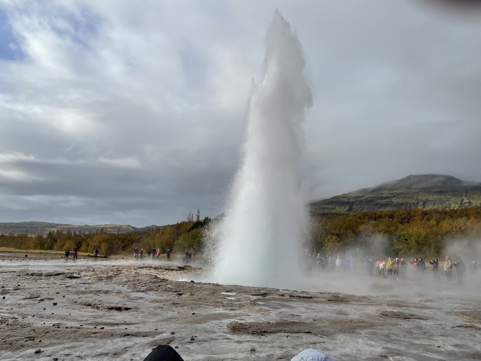 Geyser erupting with spectators around.